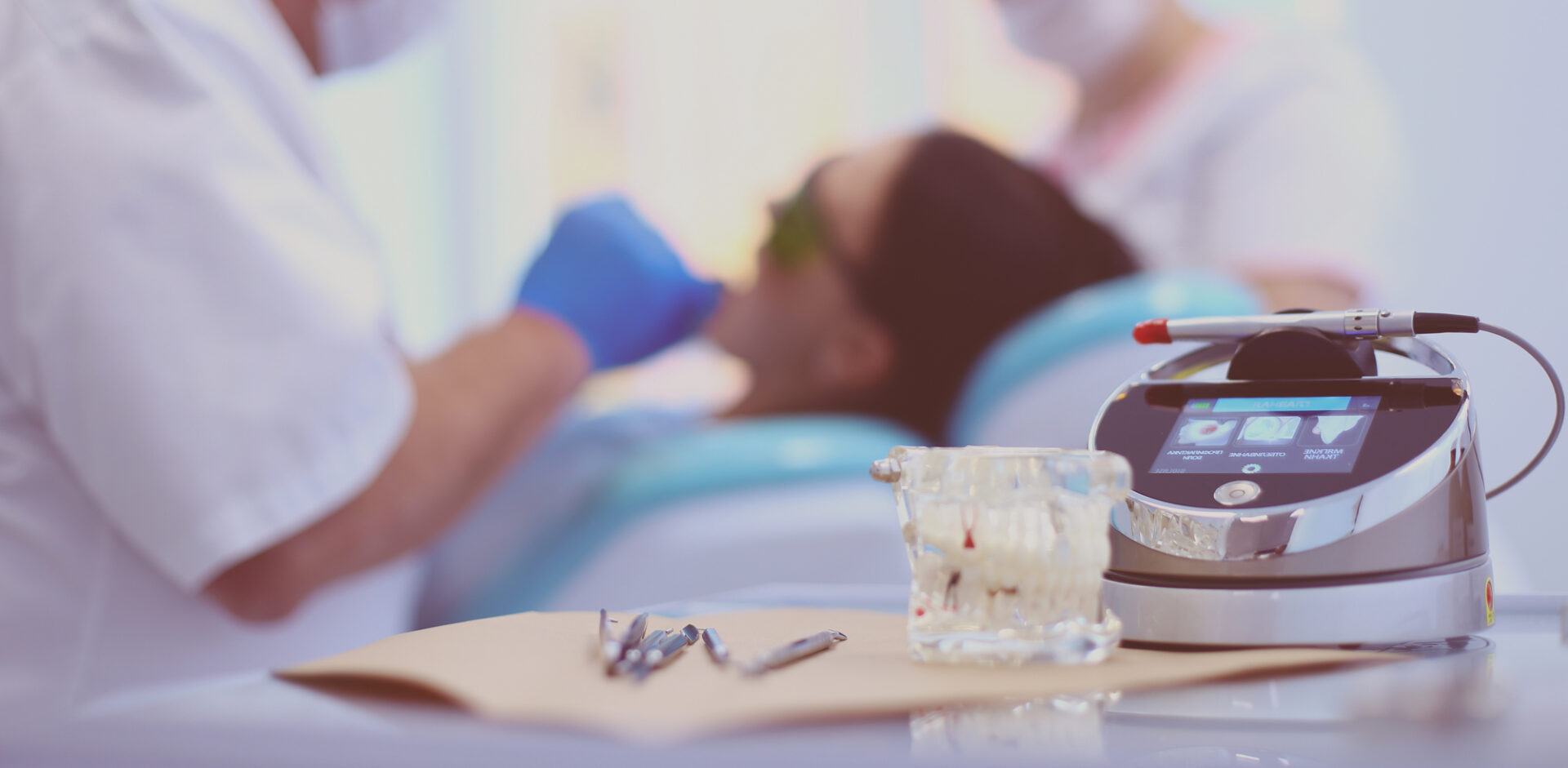 Dental equipment tools on table with dentist treating patient in background - laser dentistry