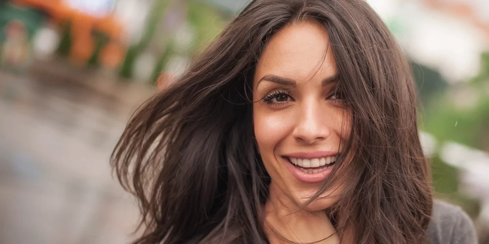 close up of smiling woman with long brown hair after leaving the dentist in McKinney TX